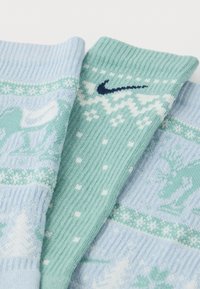 Ponožky Nike v barevném provedení světle modré a mátově zelené, s žebrovanou texturou a zimními vzory stromů a sněhových vloček.