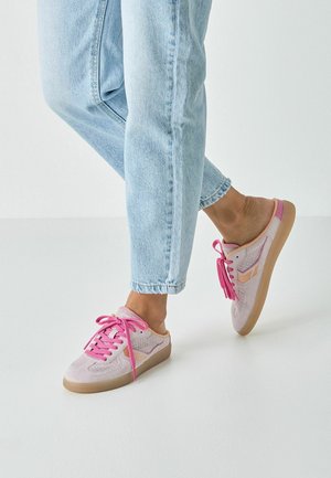 Nízkoprofilová teniska z jemné růžové semišové kůže s detaily z látkové síťoviny, růžovými tkaničkami a pryžovou podrážkou. Obsahuje decentní boční logo a ozdobné střapce.