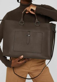 Brun texturerad läder tote-väska med dubbla handtag, en framficka och en avtagbar axelrem. Spännen förbättrar funktionaliteten.