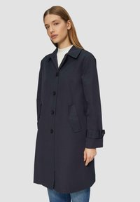 Marineblauwe trenchcoat met een kraag, knoopsluiting aan de voorkant en zijzakken. Gemaakt van glad materiaal met verstelbare manchetten en een rechte snit.