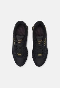 Black athletic sneakers with a textured fabric upper, contrasting smooth leather accents, and laces; features a gold logo and a rubber outsole.