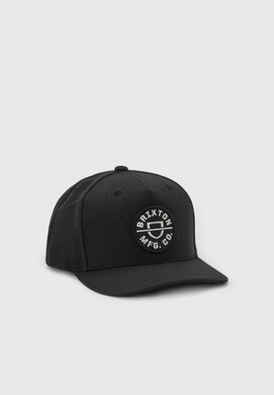 Black cap made from sturdy fabric, featuring a white circular logo with "Brixton MFG Co." The cap has a structured shape and flat brim.
