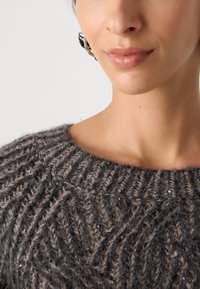 Gruby sweter w odcieniach szaro-brązowych, z teksturowanym wzorem i subtelnymi detalami z cekinów, o szerokim dekolcie.