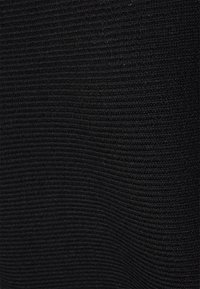 Svart ribbad tyg med en texturerad yta, med parallella spår som skapar ett konsekvent mönster genom hela materialet.