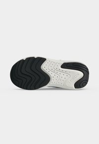 Semelle de basket blanche avec des motifs ondulés noirs, de multiples petits trous de ventilation et le nom de la marque Geox embossé près du talon.