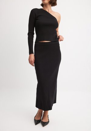 Ensemble en tricot côtelé noir en deux pièces comprenant un crop top à épaule unique et une jupe à longueur de cheville. Le tissu semble lisse avec une silhouette ajustée.