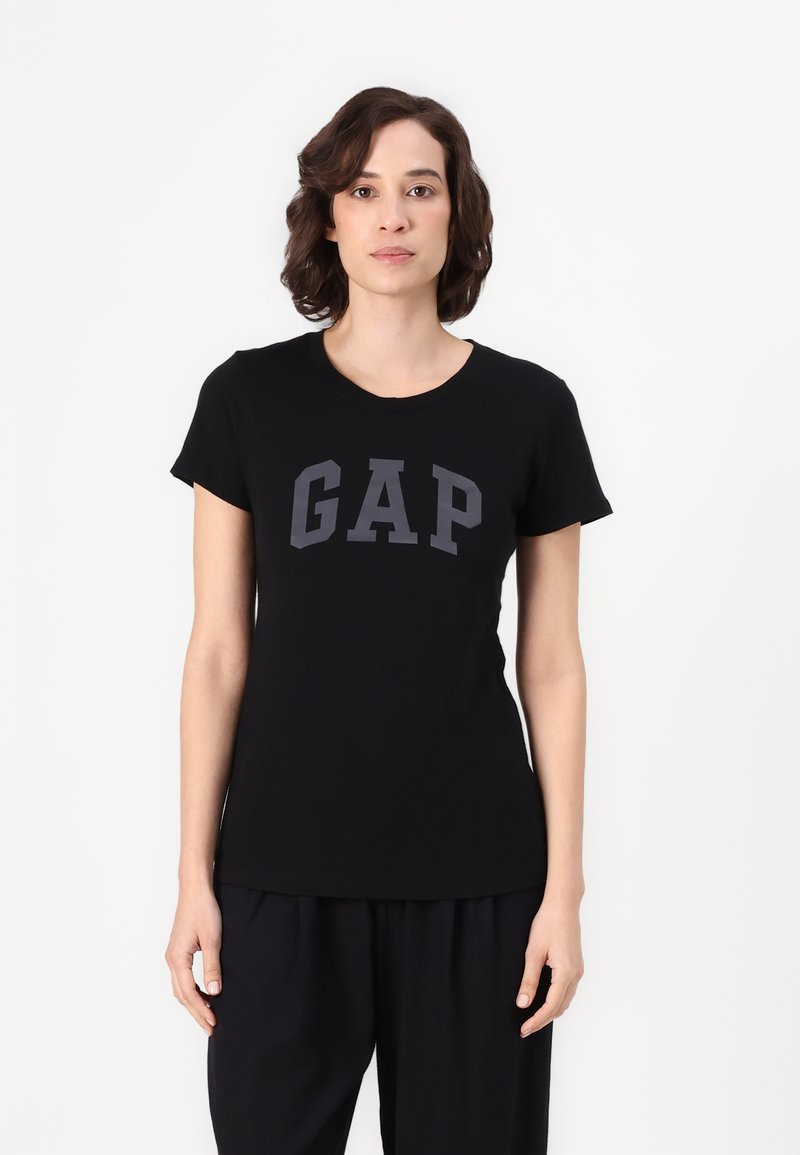 Camiseta de algodón negra con cuello redondo y mangas cortas, con "GAP" impreso en gris oscuro en el pecho.