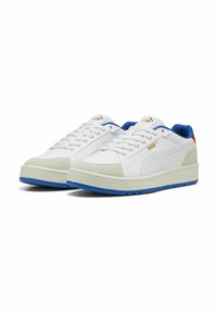 Sneaker bianche con tomaia in pelle e camoscio, dettagli blu e rossi, e suola ammortizzata. Presentano lacci e logo dorato sulla linguetta.