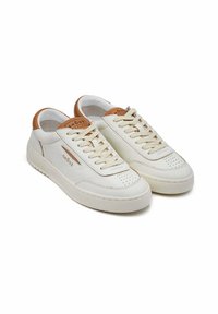 Sneaker bianche in pelle con accenti color tan, punta perforata e lacci a contrasto. Suola piatta e dettaglio etichetta con marchio sulla linguetta.