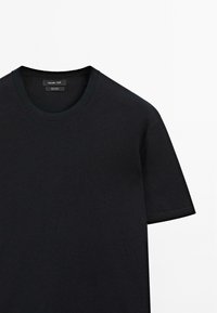 Černé bavlněné tričko s kulatým výstřihem, krátkými rukávy a hladkou texturou. Štítek našívaný na krku. Jednoduchý design, bez vzorů.