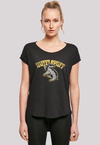 Svart kortermet t-skjorte med et gult og grått "Hufflepuff" grafikk med et grevlingdesign foran, myk stoff, avslappet passform.