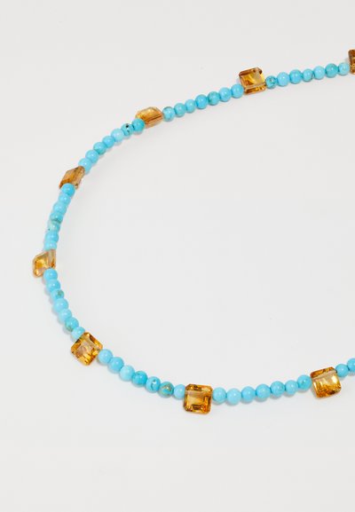 Κολιέ από τυρκουάζ χάντρες με στρογγυλές χάντρες διασκορπισμένες μ�ε ορθογώνιες πέτρες σε χρώμα κεχριμπαριού, που παρουσιάζει λείο υφή και έντονη αντίθεση χρωμάτων.