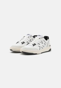 Pair of white and black Michael Kors sneakers with white laces on a light gray background, angled to show front and side details.