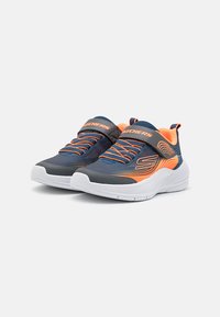 Baskets de sport bleues avec des accents orange, tissu texturé, lacets élastiques avec une bande auto-agrippante, et une semelle blanche rembourrée.