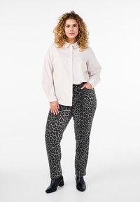 Helles rosa Button-up-Hemd, graue Leopardenmuster-Hose und schwarze Stiefeletten. Das Hemd hat einen klassischen Kragen; die Hose weist ein strukturiertes Muster auf.