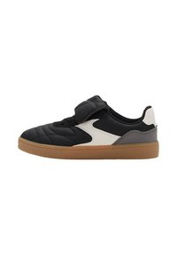 Sneaker nera trapuntata con pannello laterale bianco e grigio, caratterizzata da un tallone grigio scuro e una suola in gomma marrone. Chiusura con strap in Velcro.