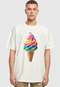 Hvid bomulds T-shirt med et farverigt isvaffel grafik, der viser en isvaffel med svulmende rosa, gul, blå og grønne farver mod en tekstureret vaffelbund.