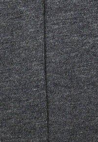 Gros plan d’un tissu tricoté gris foncé avec une couture centrale verticale au milieu.