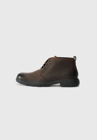 Botine din piele maro, cu vârf rotund, talpă din cauciuc negru și un design minimalist cu șireturi. Finisaj texturat cu un tab de prindere la călcâi.