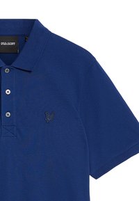 Marinblå polo med kort ärm i bomull, med en tvåknappslångning och en broderad logotyp på bröstet. Texturerad tyg.