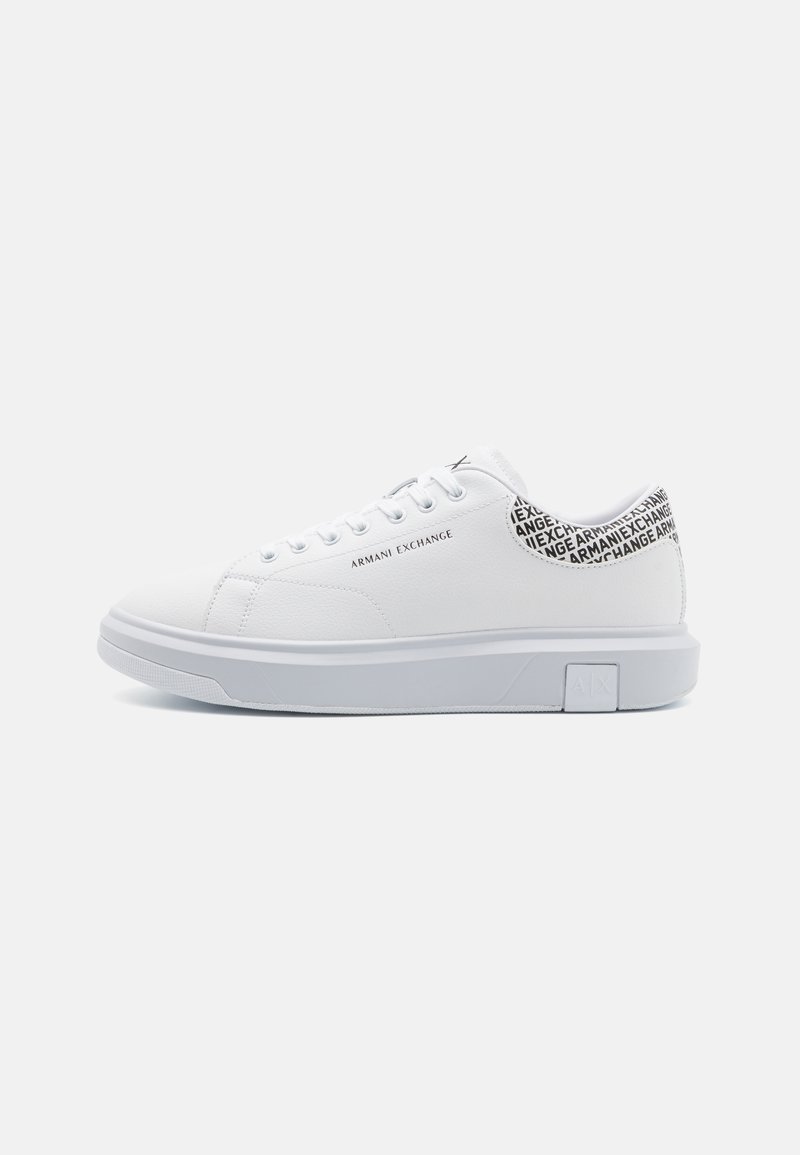 Zapatillas blancas con parte superior de cuero sintético suave, punta redonda y suela de goma blanca plana. La parte trasera presenta un patrón de texto negro con "Armani Exchange."