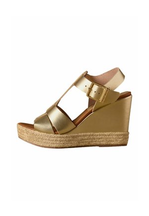 Gold wedge sandal with braided rope sole, wide straps, and adjustable buckle closure on white background.