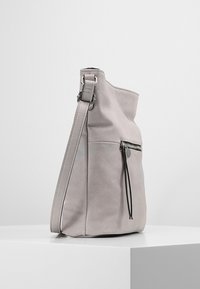 Grå läder axelväska med texturerad yta, med en dragkedjeficka på framsidan och en justerbar rem. Enkel och modern design.