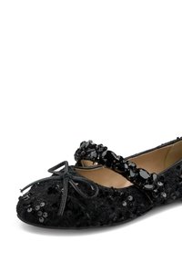 Ballet flat nera con paillettes e tessuto testurizzato, caratterizzata da un dettaglio a fiocco e una cinghia di perline sul piede per un ulteriore abbellimento.