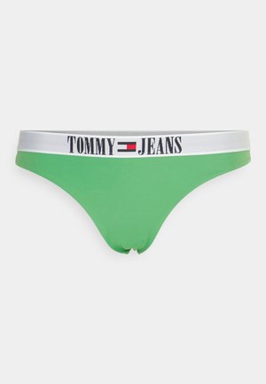 Grön bikiniunderdel i stretchigt tyg, med ett brett vitt elastiskt midjeband med "TOMMY JEANS" tryckt i svart.
