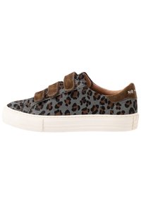 Tenisky s leopardím vzorem, s šedou srstí z semiše, hnědými suchými zipy a bílou gumovou podrážkou. Výrazné švy na stranách.