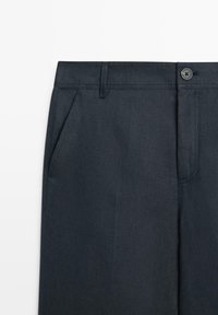 Dunkelblaue Baumwollhose mit Bund, Gürtelschlaufen, Seitentasche, Knopf und sichtbarem Reißverschluss.
