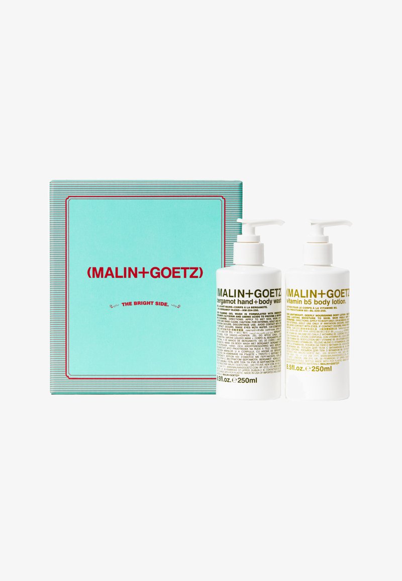 Zwei 250-ml-Pumpflaschen von Malin+Goetz mit Bergamotte-Hand- und Körperwäsche sowie Vitamin-B5-Körperlotion, zusammen mit einer türkisfarbenen Verpackung mit der Aufschrift "The Bright Side".