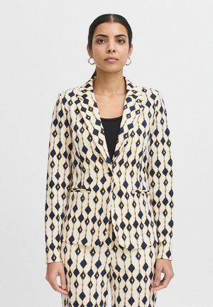 Blazer à motifs avec un fond crème, des losanges bleu marine et des accents dorés. Il dispose d'une coupe ajustée, d'un col à revers et de poches à l'avant.