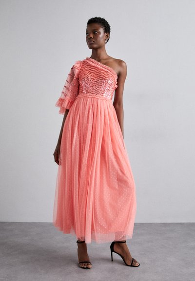 Roze tule avondjurk met één schouder, met een getextureerd lijfje versierd met pailletten. De vloeiende rok heeft stippen. Geshiedenis met zwarte hoge hakken.