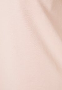 Světle růžová látka s hladkým, jemným texturem a mírně pružnými vlastnostmi, která vykazuje jednotnou plochu bez vzorů nebo ozdob.