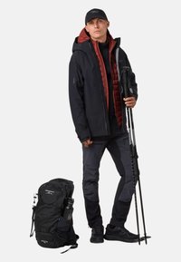 De outdoor kledingset bestaat uit een zwarte waterdichte jas, een rode geïsoleerde gilet, grijze broek, zwarte rugzak, trekkingstokken en zwarte schoenen.