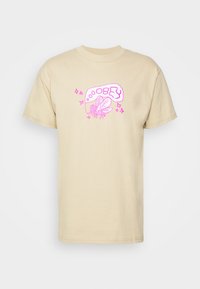 Beige bomullströja med en rosa grafisk design av en fluga och texten "OBEY" samt dekorativa stjärnor, regular fit med korta ärmar.