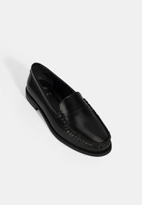 Zwarte leren instap loafers met een gladde afwerking, voorzien van decoratieve stiksels en een ronde neus. Getextureerde rubberen zool voor grip.