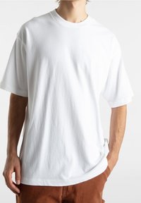 Bílý bavlněný tričko s krátkým rukávem, uvolněný střih, kulatý výstřih a hladká textura. Bez vzorů nebo viditelných log.