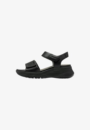 Sandal nera con cinturino regolabile, caratterizzata da una tomaia in pelle liscia e una suola in gomma testurizzata, progettata per comfort e stabilità.