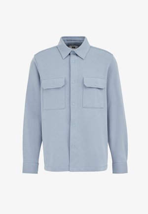 Világoskék ingdzseki, puha anyagból készült, gombbal záródó elülső résszel, két mellzsebekkel és sima textúrájú klasszikus gallérral.