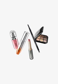Cinque prodotti per il trucco disposti artisticamente: rossetti in diverse confezioni, una palette di ombretti con otto colori e una matita eyeliner, tutti con marchio.