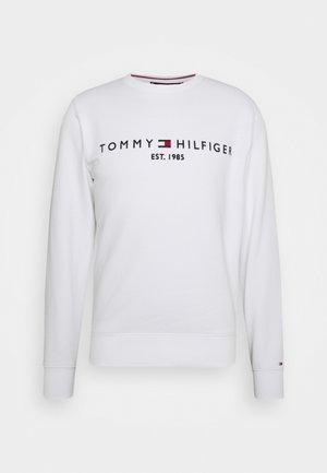 Sweatshirt blanc en mélange de coton, arborant le logo "TOMMY HILFIGER" en bleu marine avec une touche de rouge. Poignets et ourlet inférieur côtelés. Design à col rond.