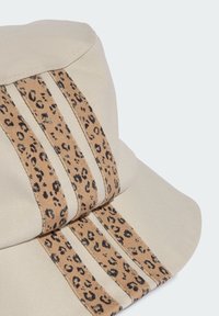 Beige cap with a structured design, featuring two leopard print stripes and textured fabric. The brim is curved, blending with the cap body.