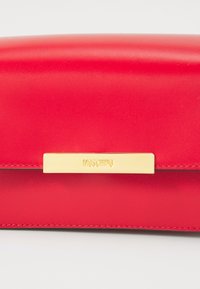 Plică roșie din piele, cu un exterior neted, accesorii din metal auriu și o placă logo texturată. Design compact, rectangular.