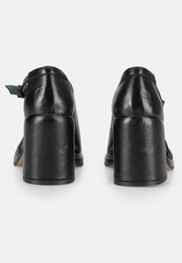 Zwarte leren blokkant schoenen met een gladde oppervlakte en een ronde achterkant, met een verstelbare band met een groene accent.