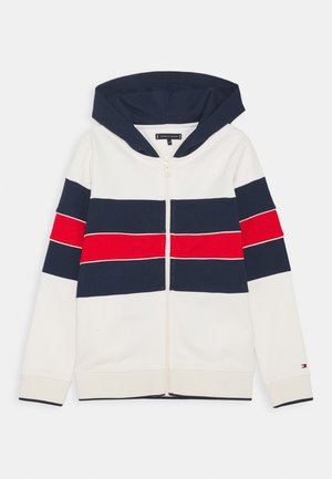 Felpa con cappuccio color crema, con strisce orizzontali blu navy e rosse. Dotata di cerniera frontale e polsini a coste. Tessuto morbido in misto cotone.