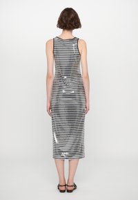 Robe midi sans manches avec une silhouette ajustée, présentant des rayures noires et argentées alternées et une finition en sequins texturée et brillante.