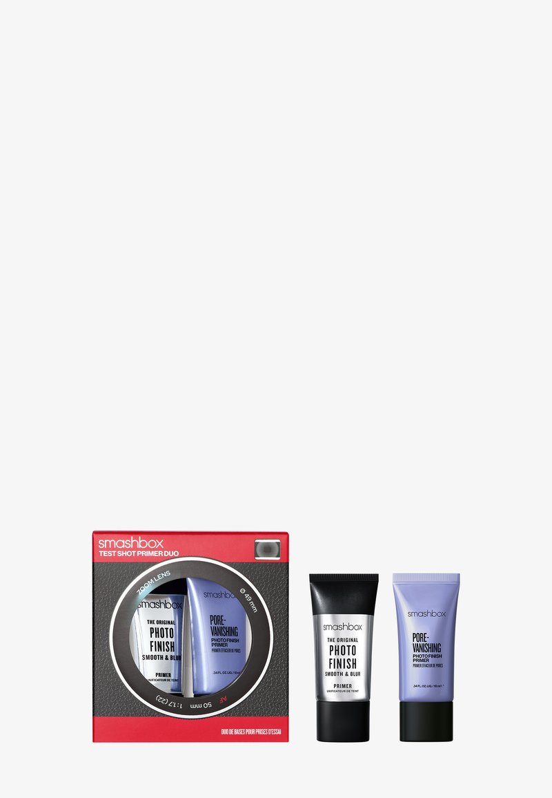De Smashbox Test Shot Primer Duo bevat twee tubes: een zwarte primer en een lila primer in een rode camera-geïnspireerde doos met een ronde venster.