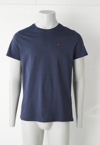 Camiseta de cuello redondo de manga corta azul marino en un maniquí blanco con un pequeño logo rojo, blanco y azul en el lado izquierdo del pecho.